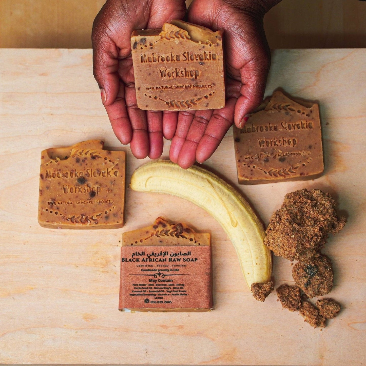 Raw butter shea African soap - hand made on wooden table -hold by hand  close up 